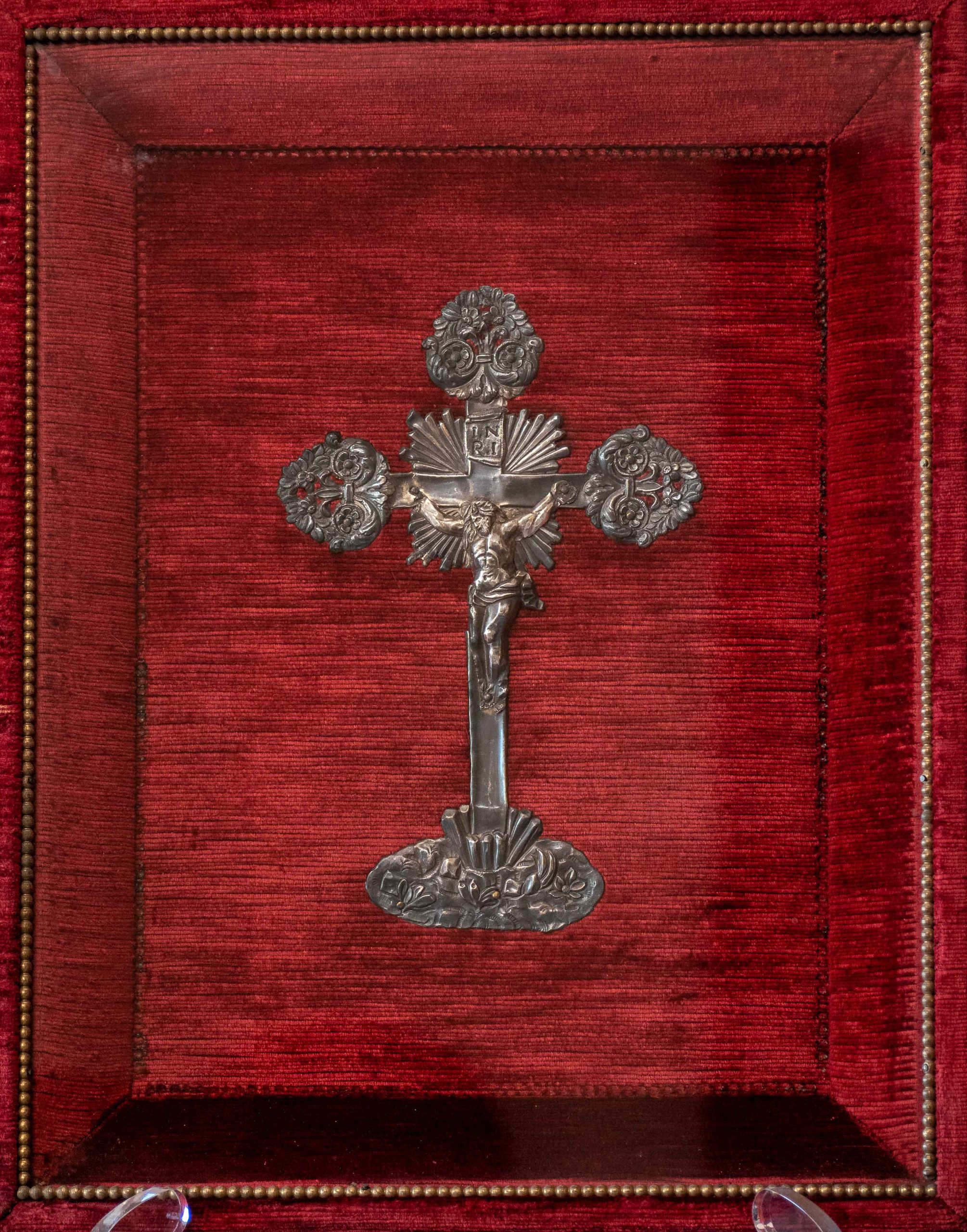Dettaglio Crocifisso in argento sbalzato XVIII.XIX d'entro teca in vetro e velluto rosso